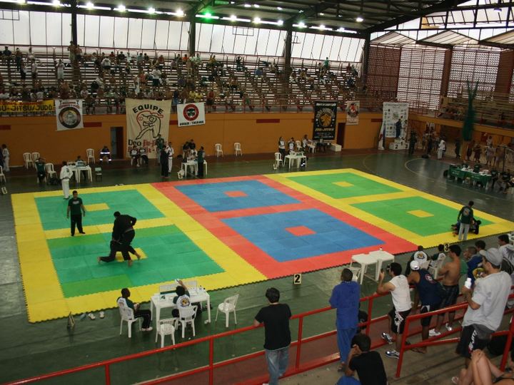 Two athletes in jiu-jitsu uniforms grappling on the mat at a championship in Brazil