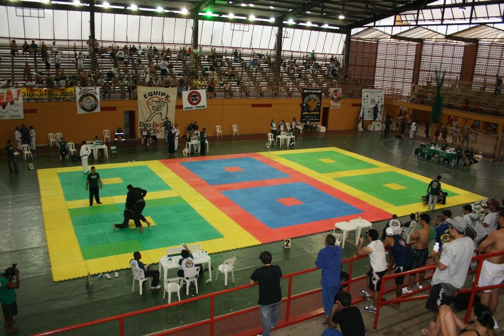 Two athletes in jiu-jitsu uniforms grappling on the mat at a championship in Brazil